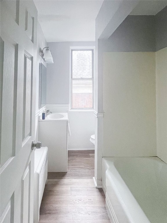 full bathroom featuring hardwood / wood-style floors, vanity, washtub / shower combination, and toilet