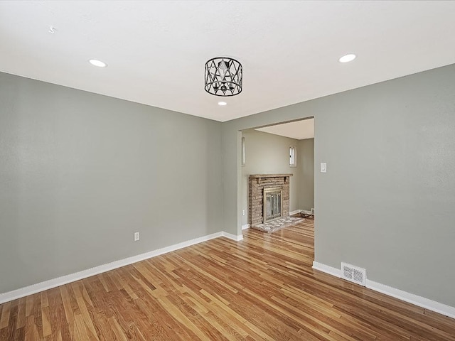 unfurnished living room featuring a stone fireplace and light hardwood / wood-style flooring