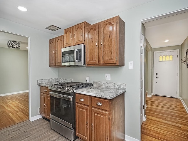 kitchen with appliances with stainless steel finishes and light hardwood / wood-style floors