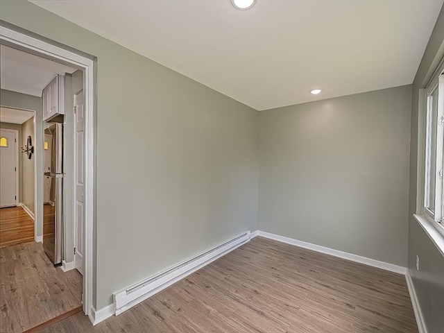 empty room with baseboard heating and light hardwood / wood-style floors