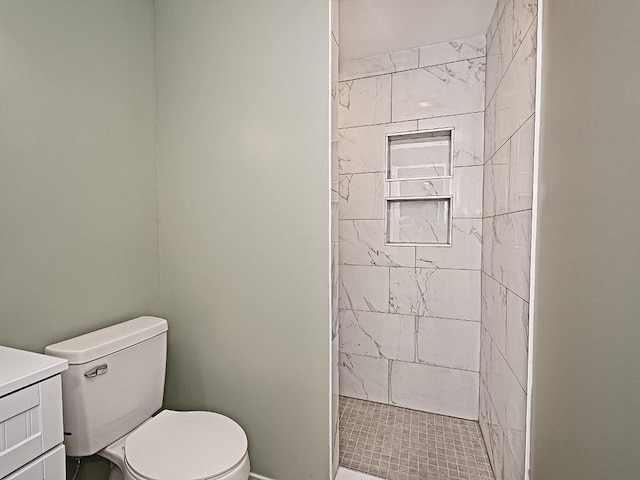 bathroom with vanity, toilet, and a tile shower