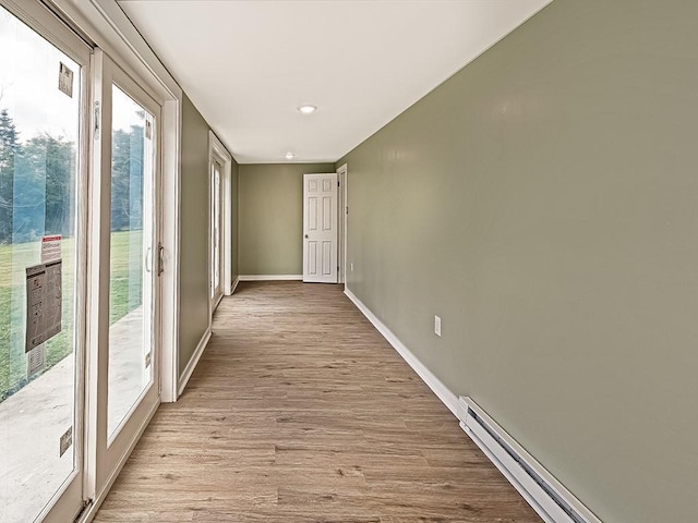 corridor with plenty of natural light, light wood-type flooring, and baseboard heating