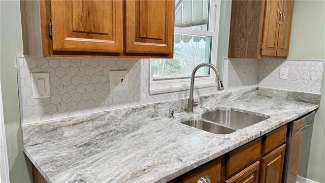 kitchen with light stone counters, dishwasher, sink, and tasteful backsplash