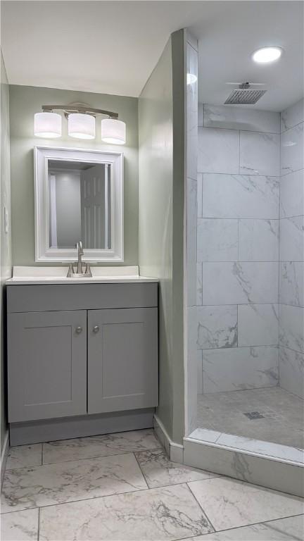 bathroom featuring a tile shower and vanity