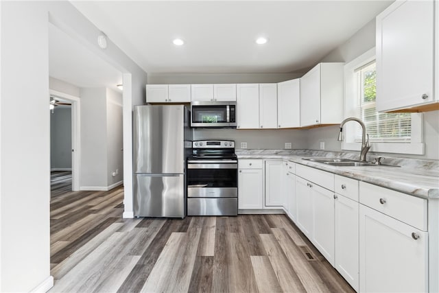 kitchen featuring sink, white cabinets, light wood-type flooring, and stainless steel appliances