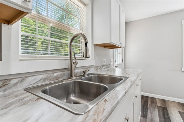 kitchen featuring sink, dark hardwood / wood-style flooring, white cabinetry, and light stone countertops