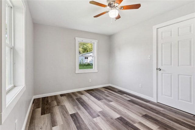 empty room featuring ceiling fan, baseboards, and wood finished floors