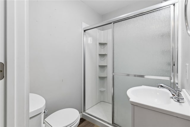 bathroom featuring walk in shower, hardwood / wood-style flooring, toilet, and vanity