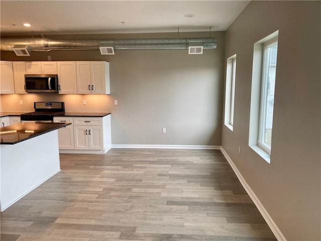 kitchen featuring white cabinetry, pendant lighting, light hardwood / wood-style flooring, and stainless steel appliances