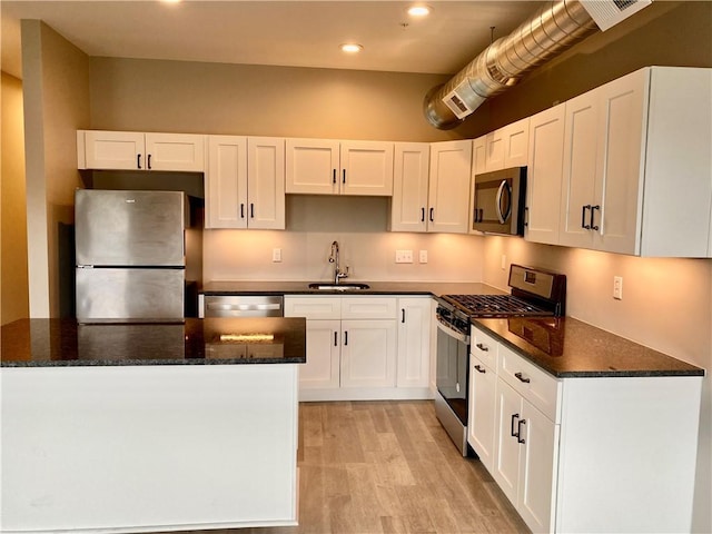 kitchen featuring white cabinetry, appliances with stainless steel finishes, sink, and dark stone countertops