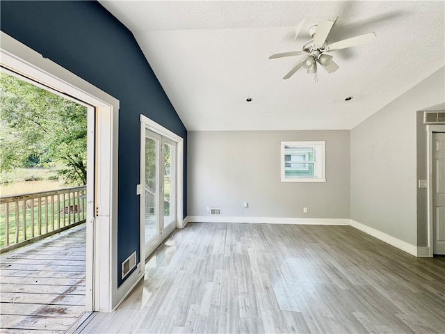 empty room featuring vaulted ceiling, a textured ceiling, ceiling fan, and light wood-type flooring