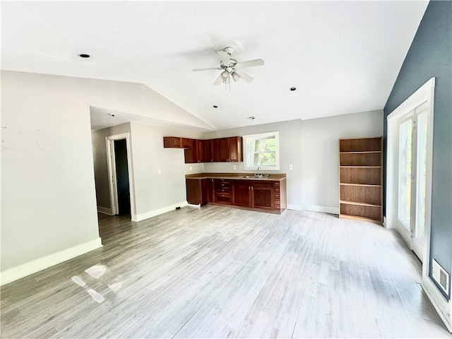 unfurnished living room with light hardwood / wood-style floors, vaulted ceiling, sink, and ceiling fan