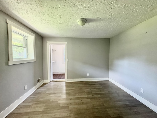 unfurnished room with a textured ceiling and wood-type flooring