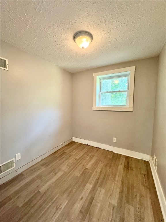 empty room with hardwood / wood-style flooring and a textured ceiling