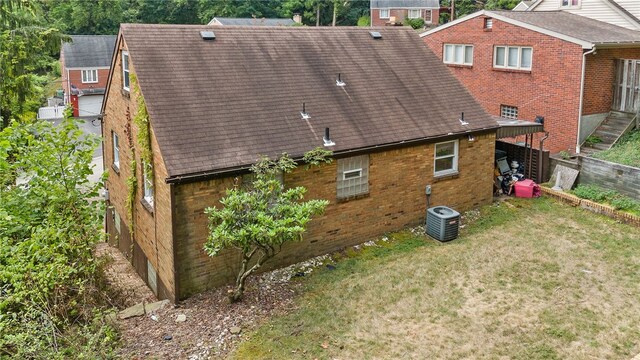 back of house with central air condition unit and a yard