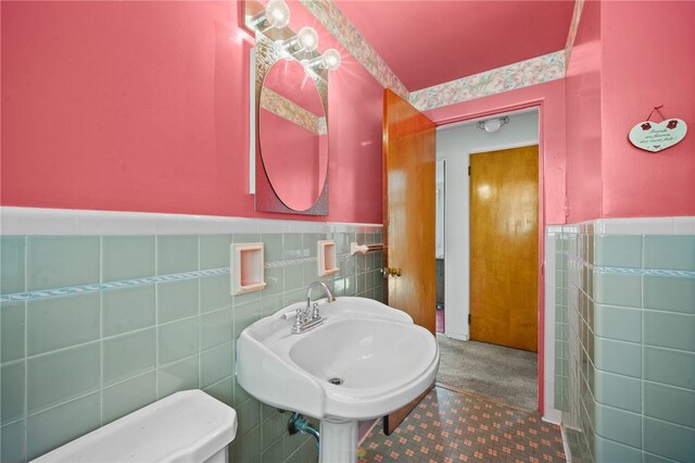 bathroom featuring toilet, tile patterned floors, backsplash, and tile walls