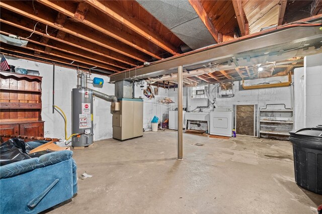 basement featuring water heater, sink, washer and clothes dryer, and heating unit