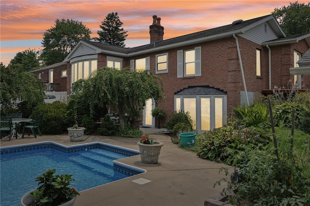 back house at dusk featuring a patio area