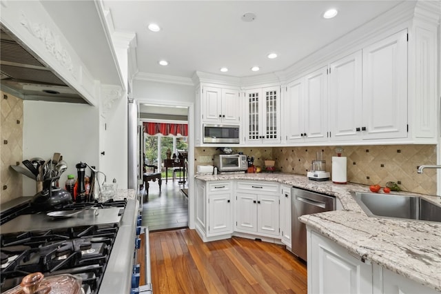 kitchen featuring premium range hood, hardwood / wood-style flooring, stainless steel appliances, and tasteful backsplash