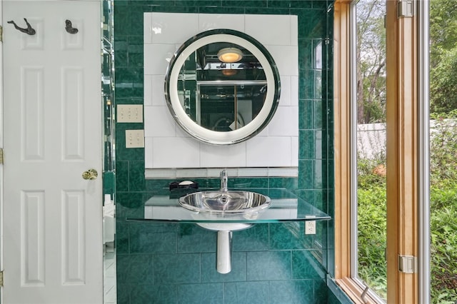 bathroom with tile walls, a healthy amount of sunlight, toilet, and sink