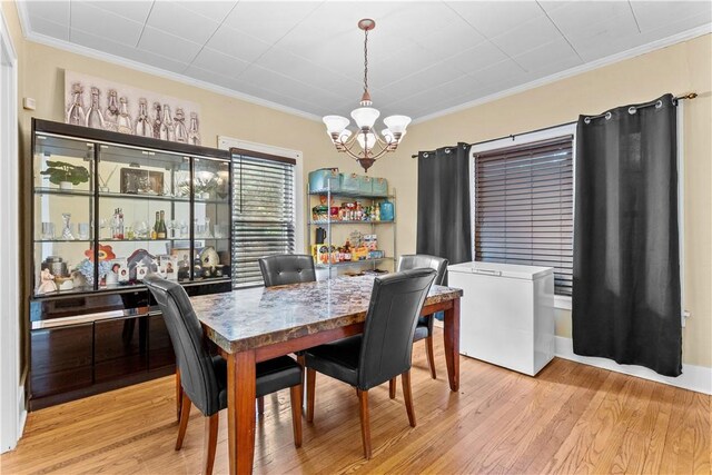 dining space with light hardwood / wood-style floors, a notable chandelier, and crown molding