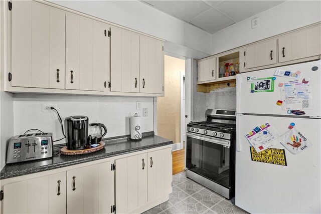 kitchen with white fridge, white cabinets, gas stove, and light hardwood / wood-style flooring