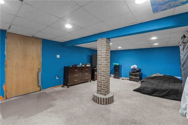 bedroom featuring a drop ceiling, light colored carpet, brick wall, and ornate columns