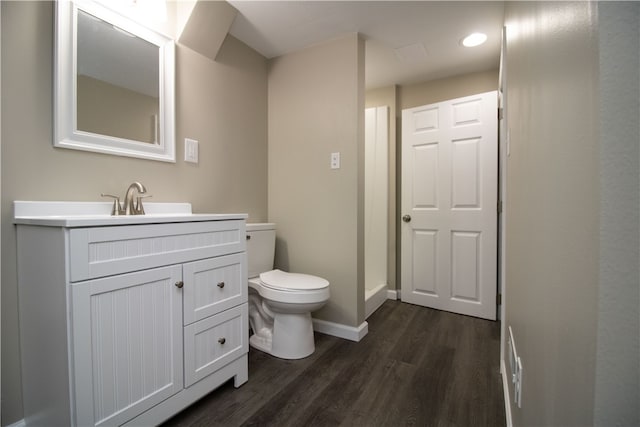 bathroom featuring toilet, vanity, baseboards, and wood finished floors