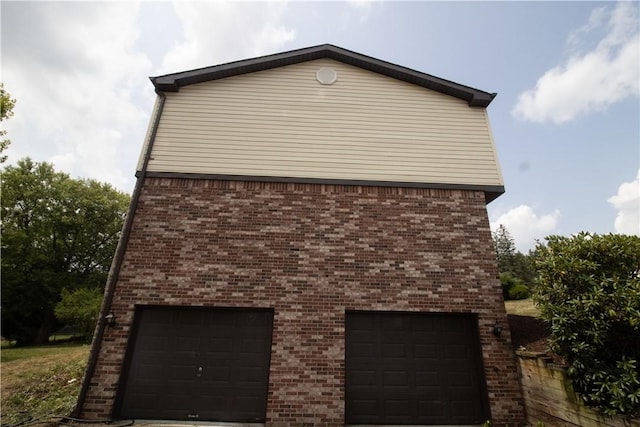 view of side of home featuring brick siding and a detached garage