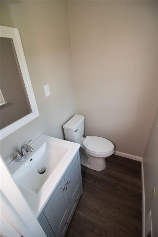 bathroom with toilet, vanity, baseboards, and wood finished floors