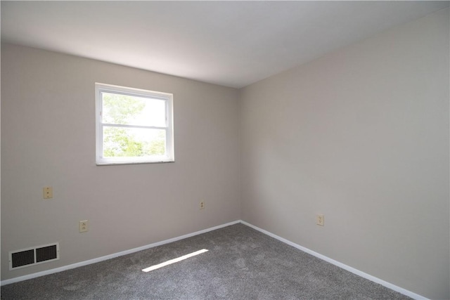 spare room with visible vents, baseboards, and dark carpet