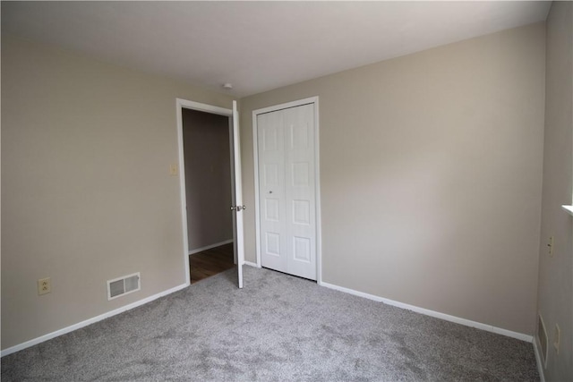 unfurnished bedroom with visible vents, carpet floors, baseboards, and a closet