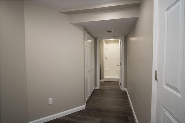 corridor with dark wood-style floors, visible vents, and baseboards