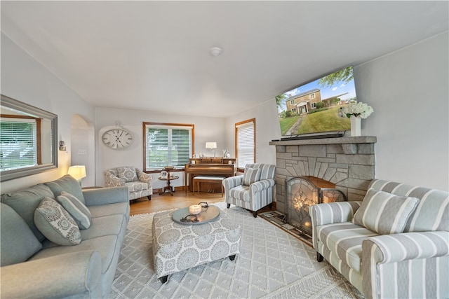 living room with light hardwood / wood-style flooring and a stone fireplace