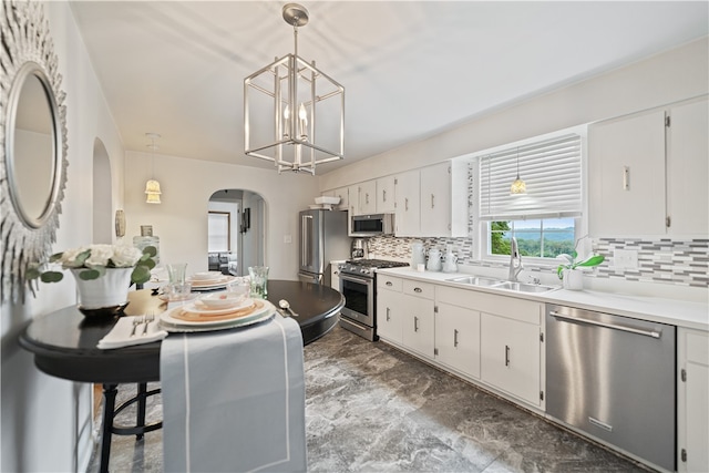 kitchen featuring white cabinets, sink, tasteful backsplash, decorative light fixtures, and stainless steel appliances