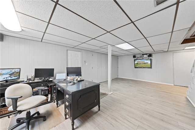 office area with wood walls, a drop ceiling, and light hardwood / wood-style floors