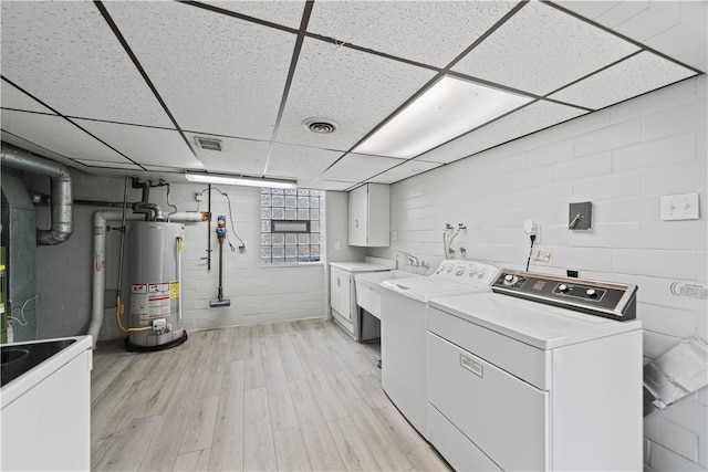 laundry room with light wood-type flooring, washing machine and dryer, gas water heater, and sink