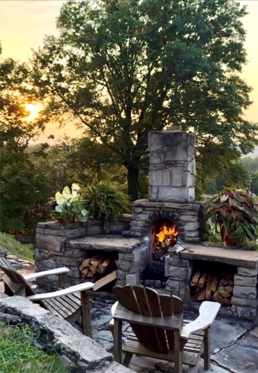 patio terrace at dusk with an outdoor stone fireplace