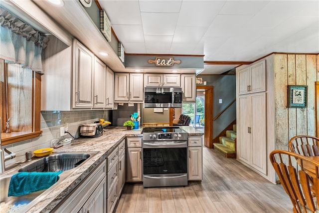 kitchen with light stone counters, backsplash, light hardwood / wood-style flooring, and appliances with stainless steel finishes