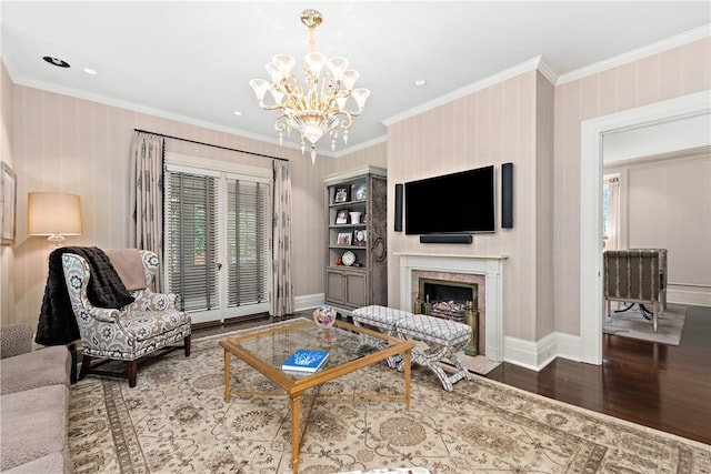 living room with a high end fireplace, ornamental molding, an inviting chandelier, and hardwood / wood-style floors