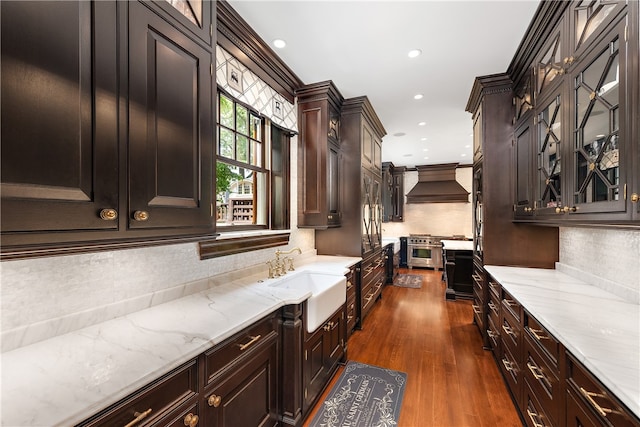 kitchen with dark wood-type flooring, custom exhaust hood, light stone counters, and ornamental molding