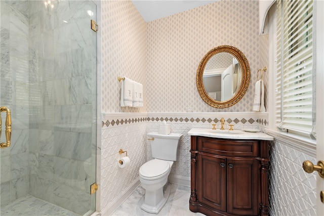 bathroom with a shower with shower door, toilet, vanity, tile walls, and tile patterned floors