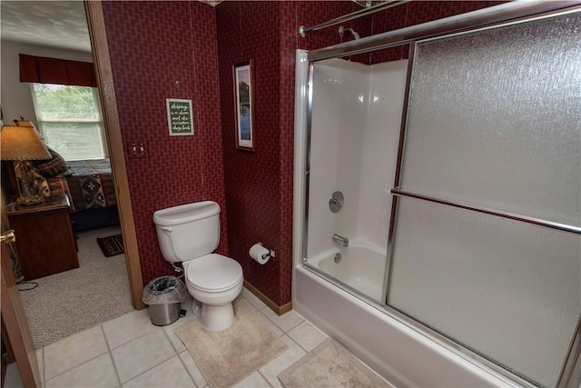 bathroom featuring tile patterned floors, toilet, and shower / bath combination with glass door