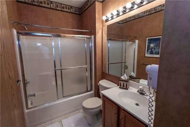 full bathroom with tile patterned flooring, vanity, bath / shower combo with glass door, and toilet