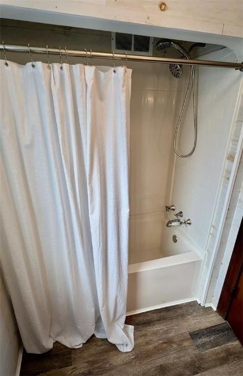 bathroom with shower / tub combo and wood-type flooring