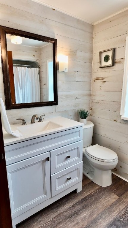 bathroom with wood walls, vanity, hardwood / wood-style flooring, and toilet