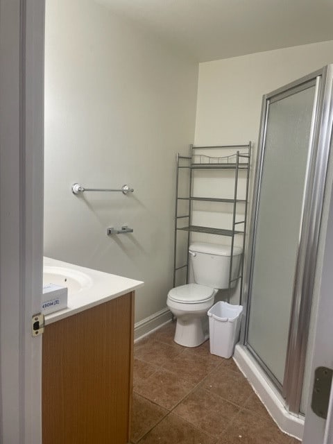 bathroom featuring tile patterned floors, vanity, walk in shower, and toilet