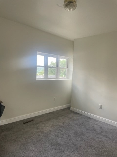 spare room featuring dark colored carpet