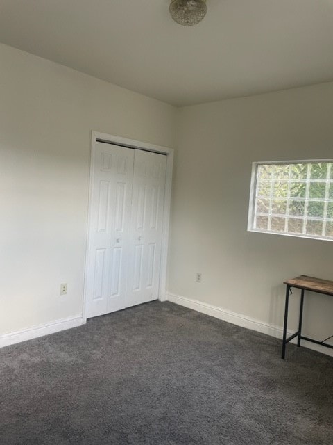 unfurnished bedroom with dark colored carpet and a closet