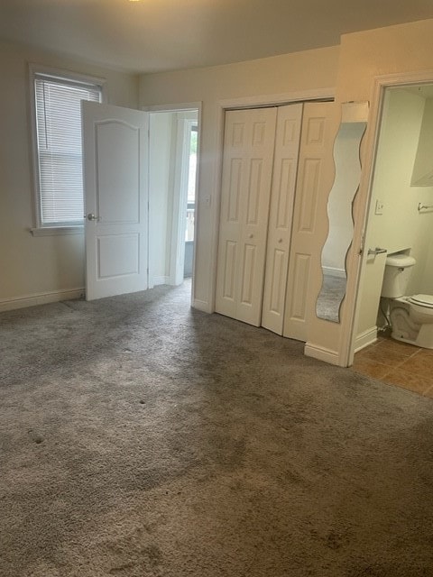 unfurnished bedroom with a closet, carpet floors, and ensuite bathroom